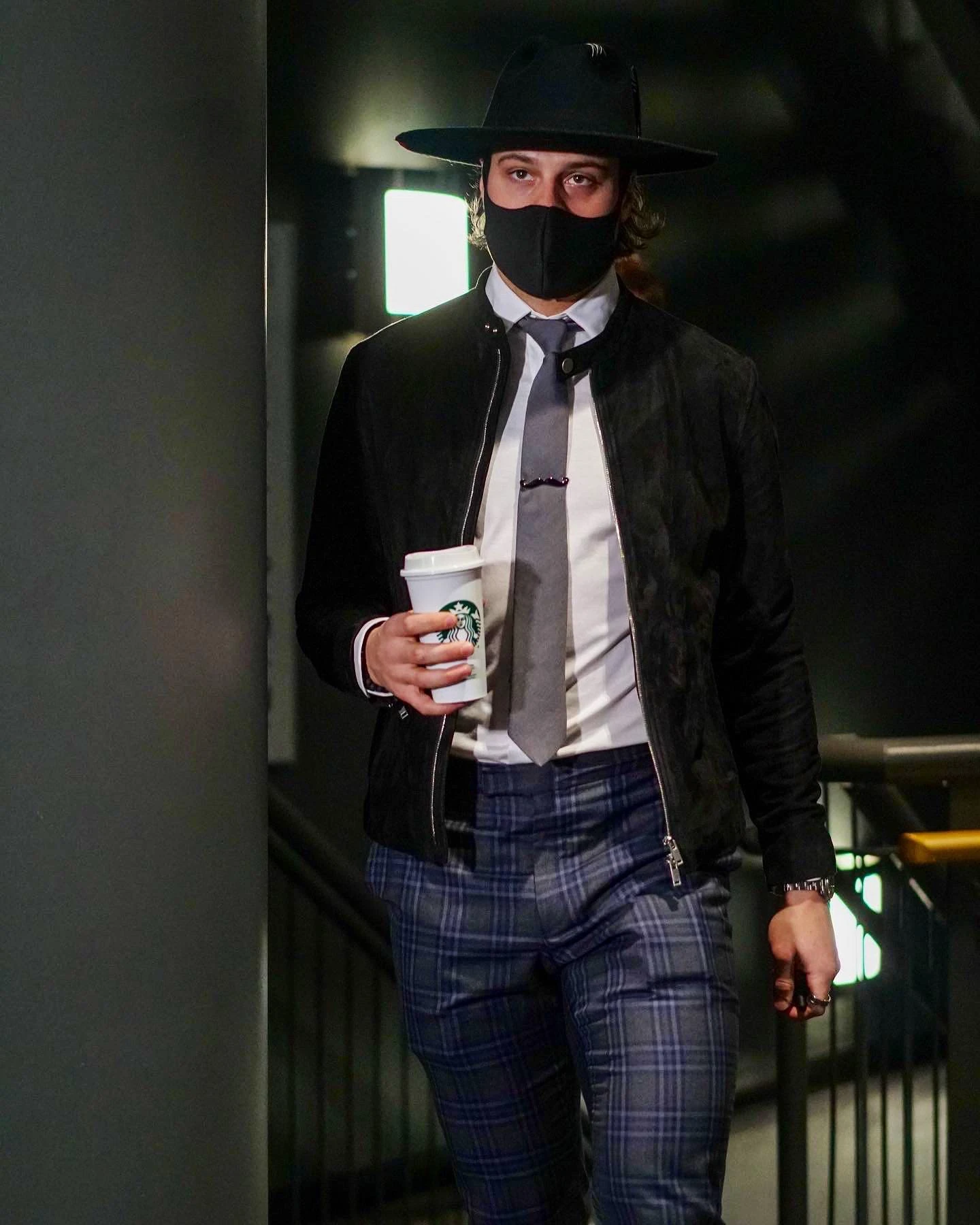 Auston Matthews in a black hat and mask wearing a sculptural piece across his tie
