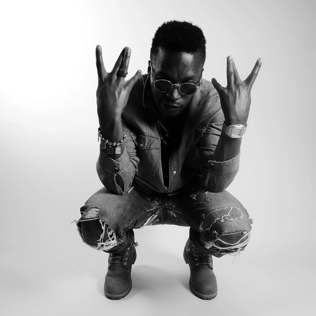 Lupe Fiasco wearing a sculptural ring and charm bracelet