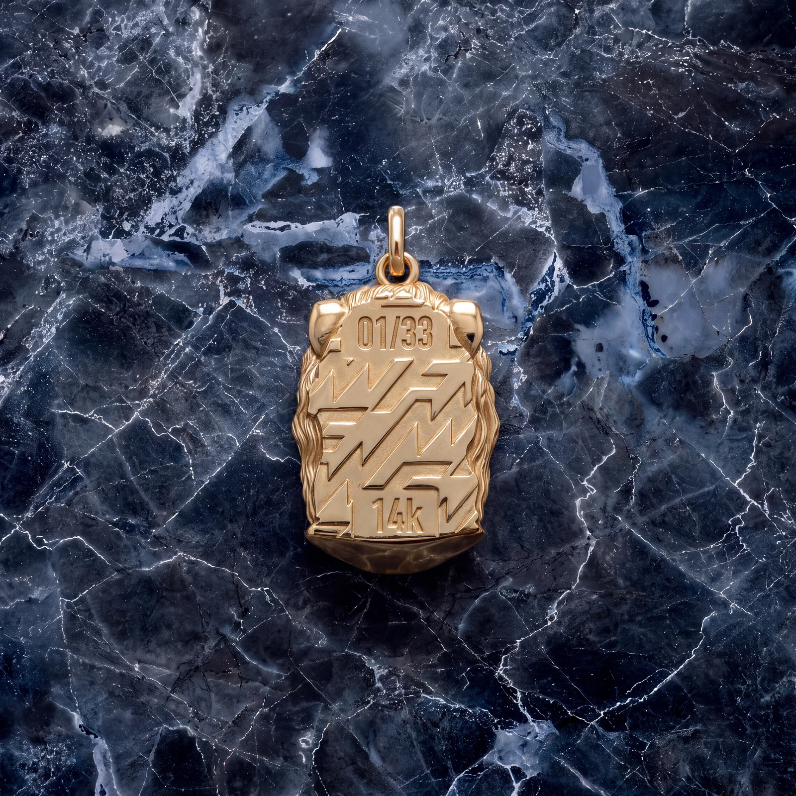 Back of the gold Hercules II Totem engraved 01/33 and 14K on dark marble